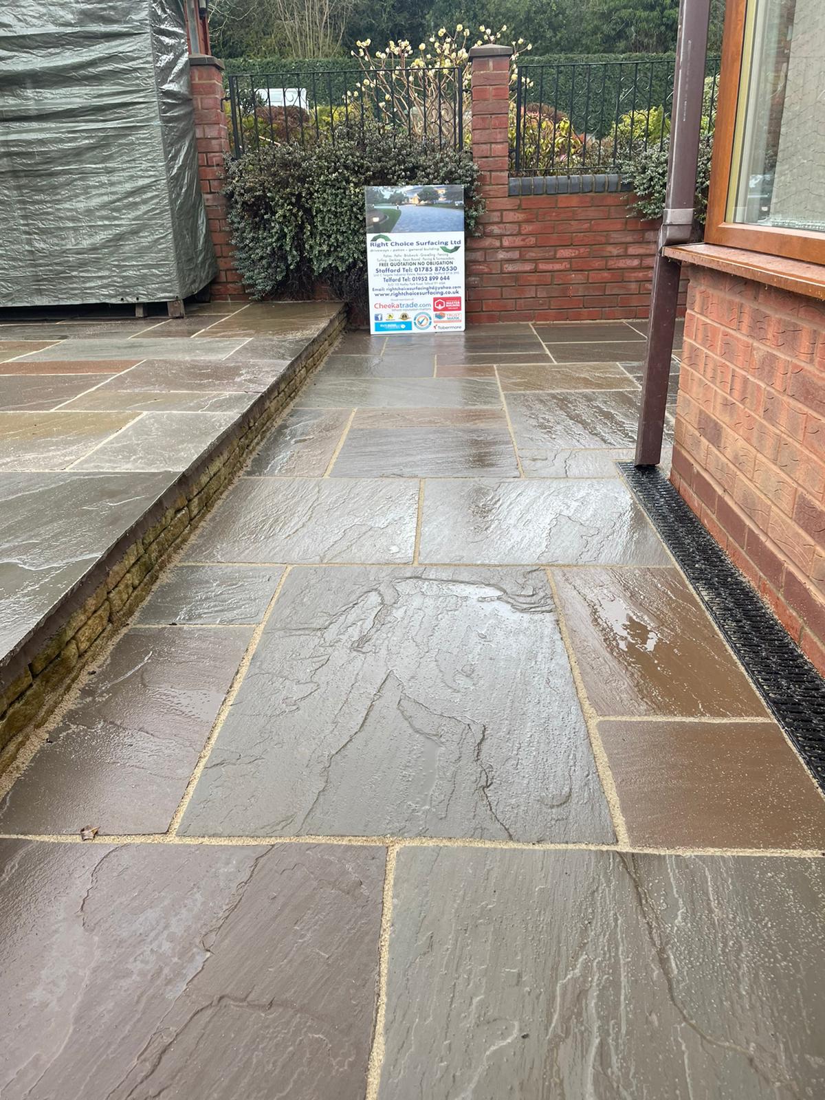 Riven sandstone wraparound patio with drainage channel
